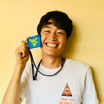 New student holds up his WVU badge next to his smiling face